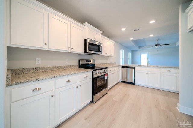 kitchen with light hardwood / wood-style flooring, ceiling fan, appliances with stainless steel finishes, light stone countertops, and white cabinets