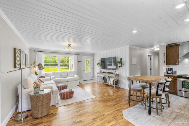 living room with wood ceiling, ornamental molding, baseboards, and light wood-style flooring