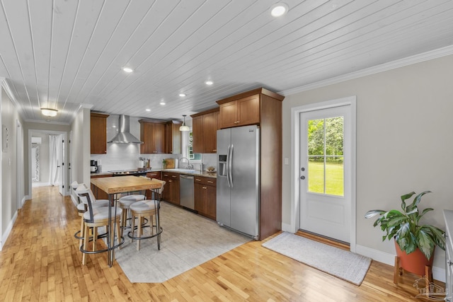 kitchen featuring wall chimney range hood, appliances with stainless steel finishes, a sink, wood counters, and recessed lighting