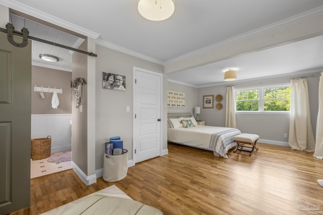 bedroom featuring a wainscoted wall, ornamental molding, baseboards, and wood finished floors