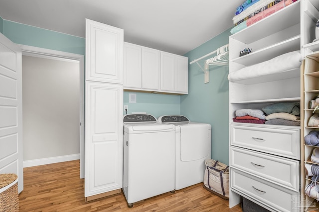 laundry area featuring separate washer and dryer, baseboards, cabinet space, and light wood-style flooring