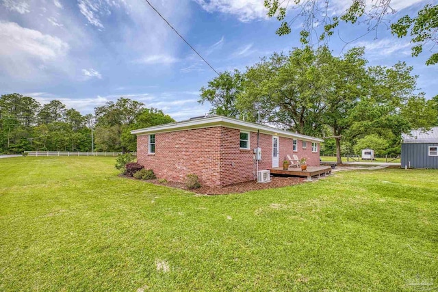 view of home's exterior with fence, a lawn, a deck, and brick siding