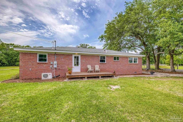 back of property featuring brick siding, a deck, ac unit, and a lawn