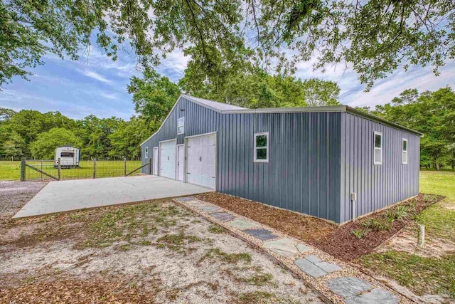 view of outbuilding with fence, an outbuilding, and driveway