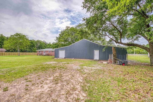view of yard featuring a pole building, fence, an outbuilding, and a detached garage