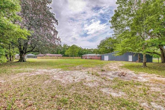 view of yard featuring fence, an outbuilding, and an outdoor structure
