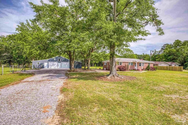 view of front of property with fence, a front lawn, an outdoor structure, and gravel driveway