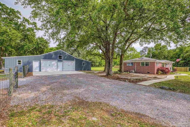 view of front of house with fence, brick siding, a garage, an outdoor structure, and gravel driveway