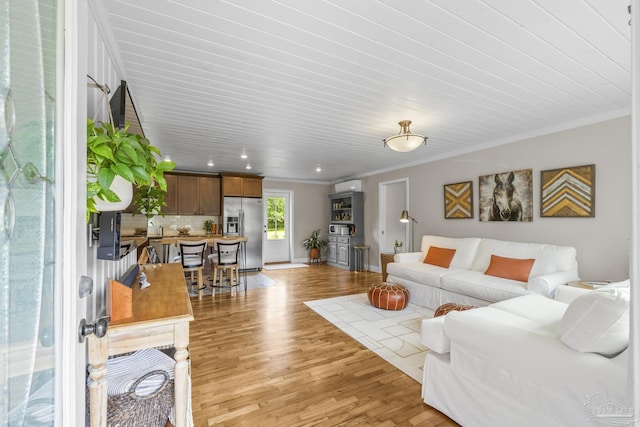 living room featuring baseboards, ornamental molding, light wood finished floors, and recessed lighting