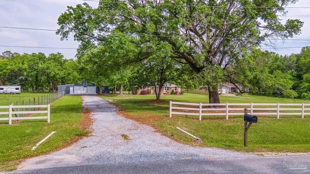 view of front of property featuring a detached garage, fence, driveway, and a front lawn