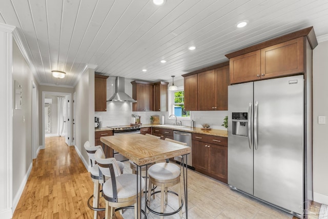 kitchen with wall chimney range hood, stainless steel appliances, recessed lighting, tasteful backsplash, and ornamental molding