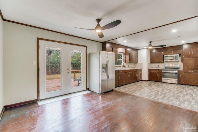 kitchen with ceiling fan, light countertops, light wood finished floors, backsplash, and stainless steel appliances