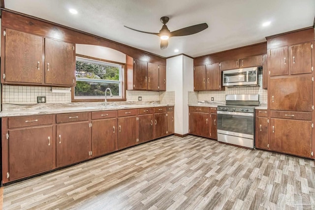 kitchen with a sink, tasteful backsplash, a ceiling fan, and stainless steel appliances