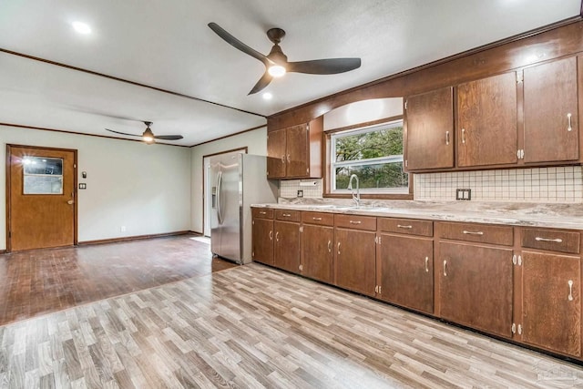 kitchen featuring stainless steel refrigerator with ice dispenser, a ceiling fan, a sink, and decorative backsplash