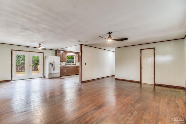 unfurnished living room with a sink, baseboards, ceiling fan, and french doors