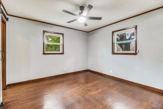 empty room with wood-type flooring, baseboards, ornamental molding, and a wealth of natural light