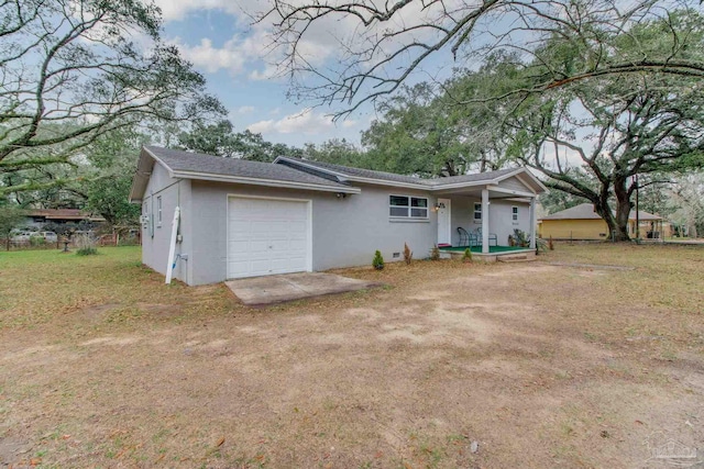 ranch-style home with roof with shingles, an attached garage, dirt driveway, stucco siding, and covered porch