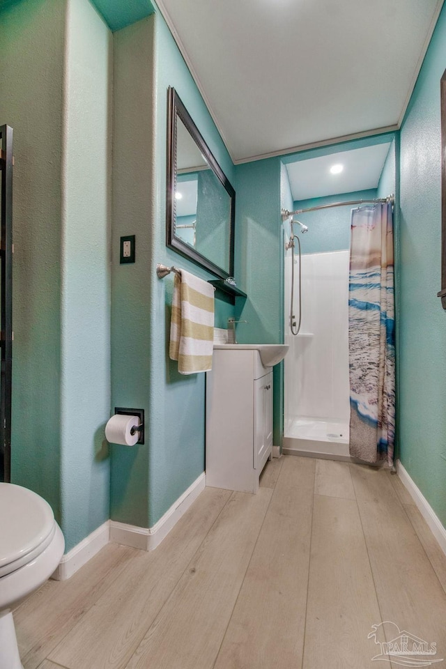 bathroom featuring vanity, wood finished floors, toilet, baseboards, and a stall shower