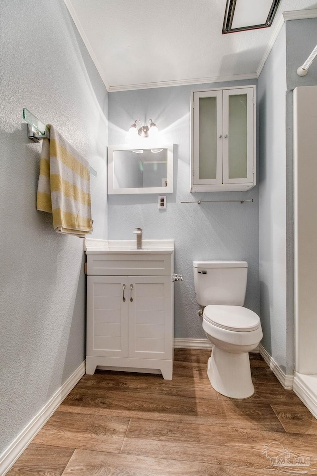 bathroom featuring toilet, baseboards, wood finished floors, and vanity