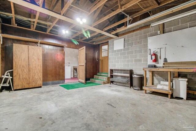 unfinished below grade area featuring stairs, washer / clothes dryer, and concrete block wall