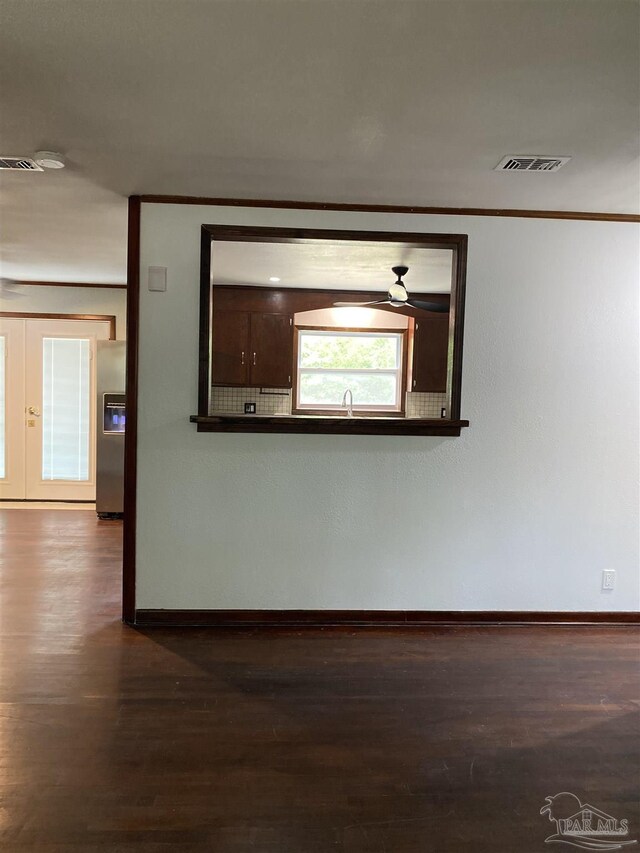 unfurnished room with visible vents, a ceiling fan, baseboards, and dark wood finished floors
