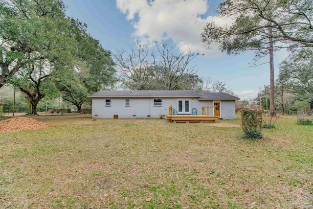 rear view of property with french doors, a wooden deck, and a yard