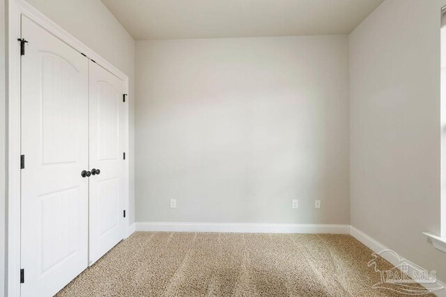 unfurnished bedroom featuring baseboards, a closet, and light colored carpet