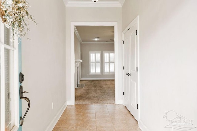 hallway with light tile patterned floors, baseboards, crown molding, and light colored carpet