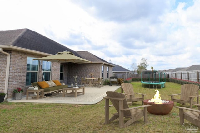 back of property featuring a fire pit, a trampoline, a patio area, and a fenced backyard