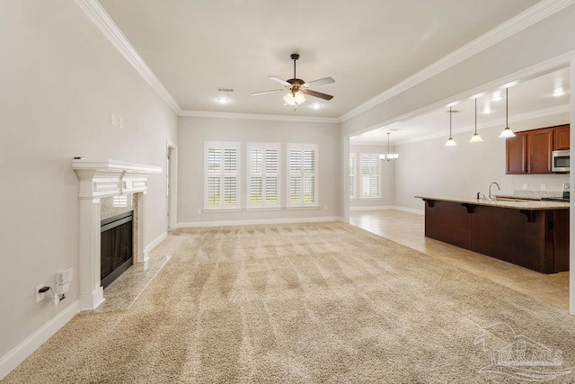 unfurnished living room featuring baseboards, a high end fireplace, light colored carpet, ornamental molding, and ceiling fan with notable chandelier