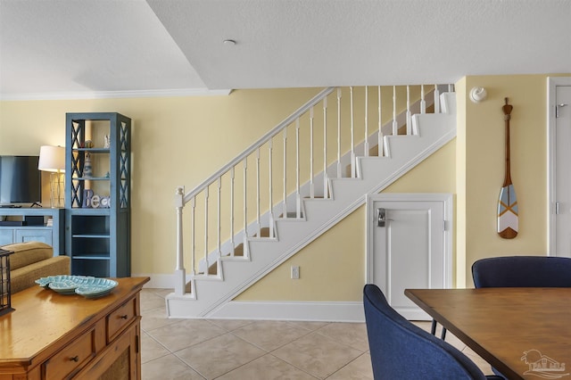 interior space with ornamental molding, tile patterned flooring, a textured ceiling, and baseboards