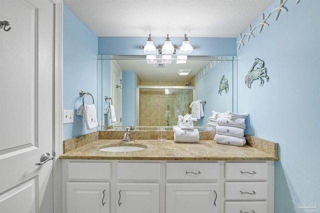 full bath featuring a textured ceiling, a shower stall, and vanity