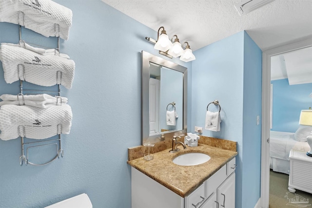 ensuite bathroom featuring toilet, a textured ceiling, connected bathroom, and vanity