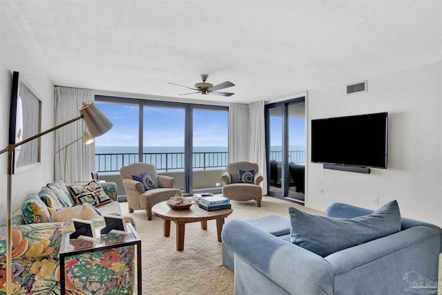 living room with ceiling fan, light colored carpet, and a textured ceiling