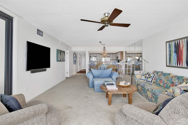 living room featuring light colored carpet and ceiling fan with notable chandelier