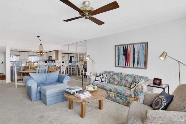 carpeted living room featuring ceiling fan with notable chandelier