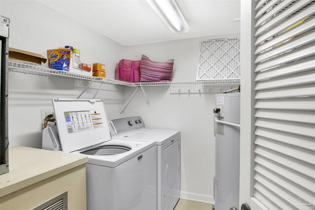 laundry room featuring electric water heater, washing machine and clothes dryer, and a textured ceiling