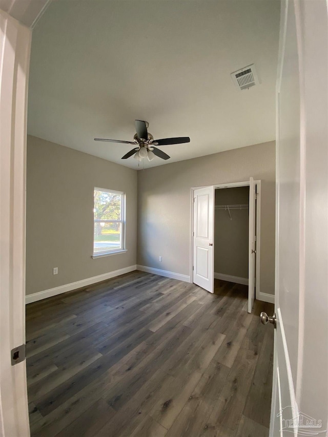 unfurnished bedroom with ceiling fan, a closet, and dark hardwood / wood-style floors