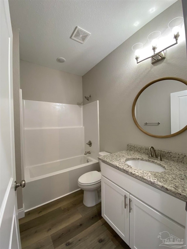 full bathroom with hardwood / wood-style floors, a textured ceiling, toilet, shower / tub combination, and vanity