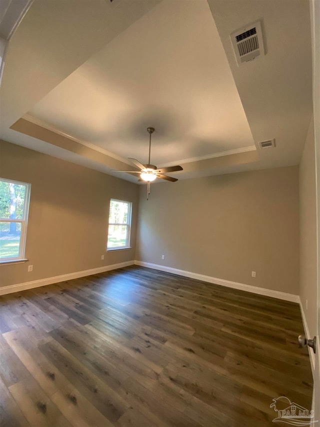 empty room with a raised ceiling, ceiling fan, and dark hardwood / wood-style flooring