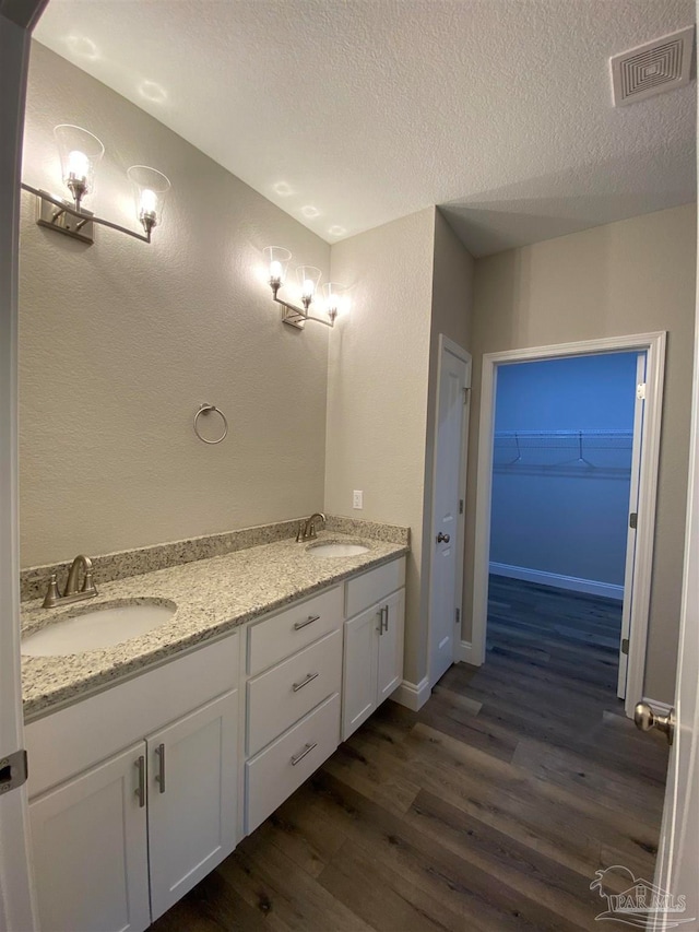 bathroom featuring vanity, wood-type flooring, and a textured ceiling