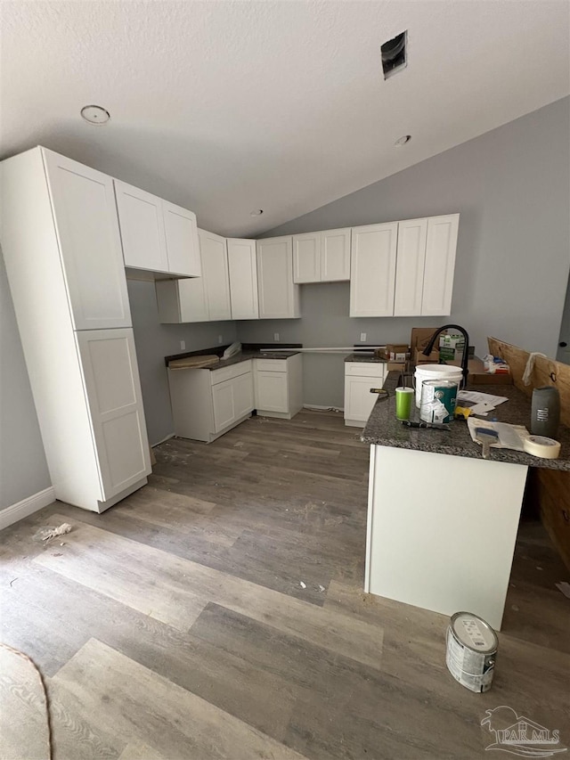 7147 Heath Rd, Milton, FL 32570 - kitchen with lofted ceiling, wood finished floors, white cabinetry, and baseboards