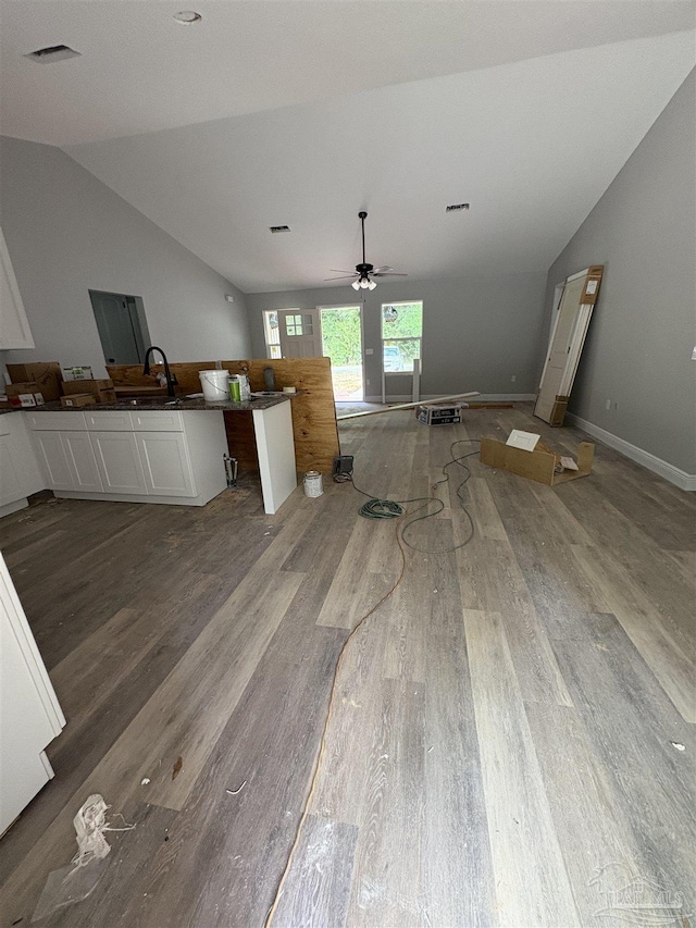 7147 Heath Rd, Milton, FL 32570 - kitchen with vaulted ceiling, wood finished floors, white cabinetry, dark countertops, and a sink