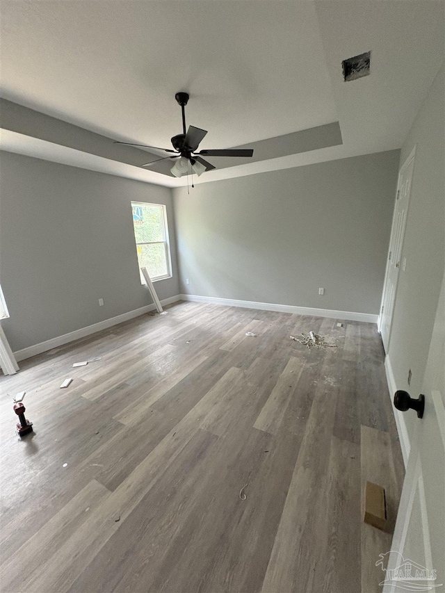 7147 Heath Rd, Milton, FL 32570 - empty room featuring a ceiling fan, baseboards, wood finished floors, and a tray ceiling