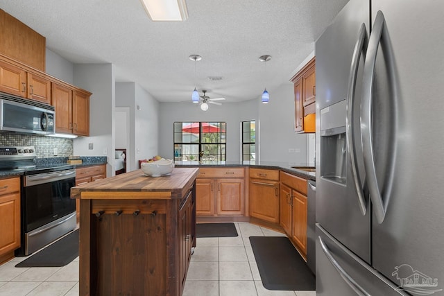 3849 Saber Tooth Cir, Gulf Breeze, FL 32563 - kitchen featuring appliances with stainless steel finishes, wood counters, backsplash, light tile patterned floors, and a peninsula
