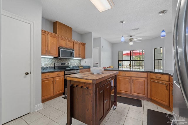 3849 Saber Tooth Cir, Gulf Breeze, FL 32563 - kitchen featuring appliances with stainless steel finishes, wooden counters, light tile patterned flooring, decorative backsplash, and a textured ceiling