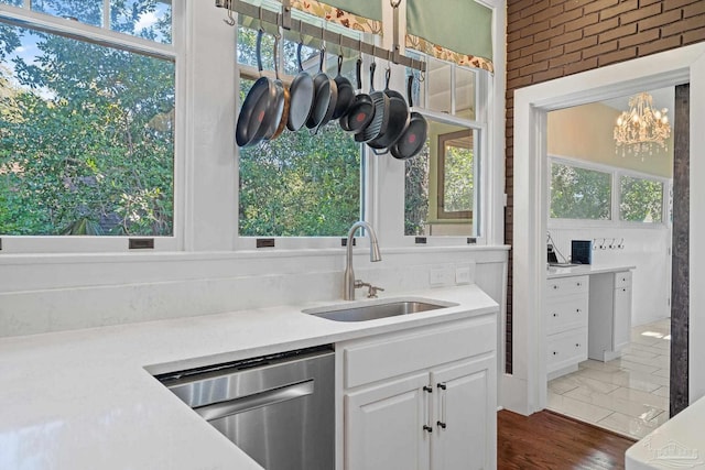 kitchen featuring stainless steel dishwasher, white cabinets, sink, and a wealth of natural light