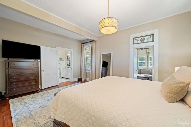 bedroom with hardwood / wood-style floors, ornamental molding, and ensuite bath