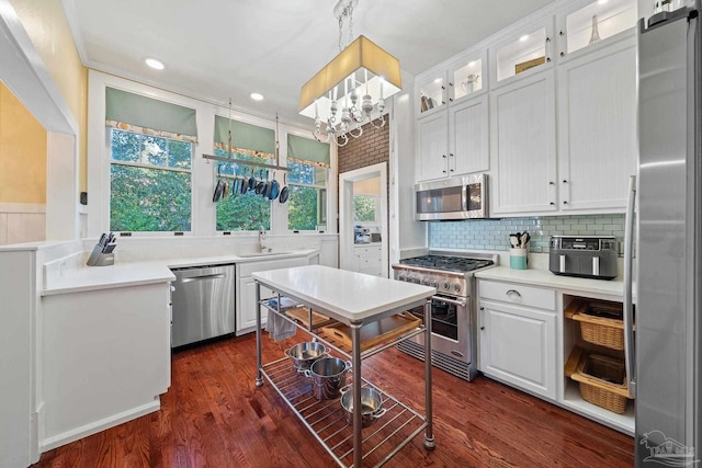 kitchen with decorative light fixtures, dark hardwood / wood-style flooring, white cabinets, appliances with stainless steel finishes, and sink