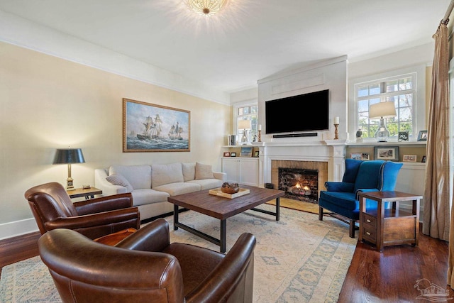 living room with a fireplace, crown molding, and dark wood-type flooring